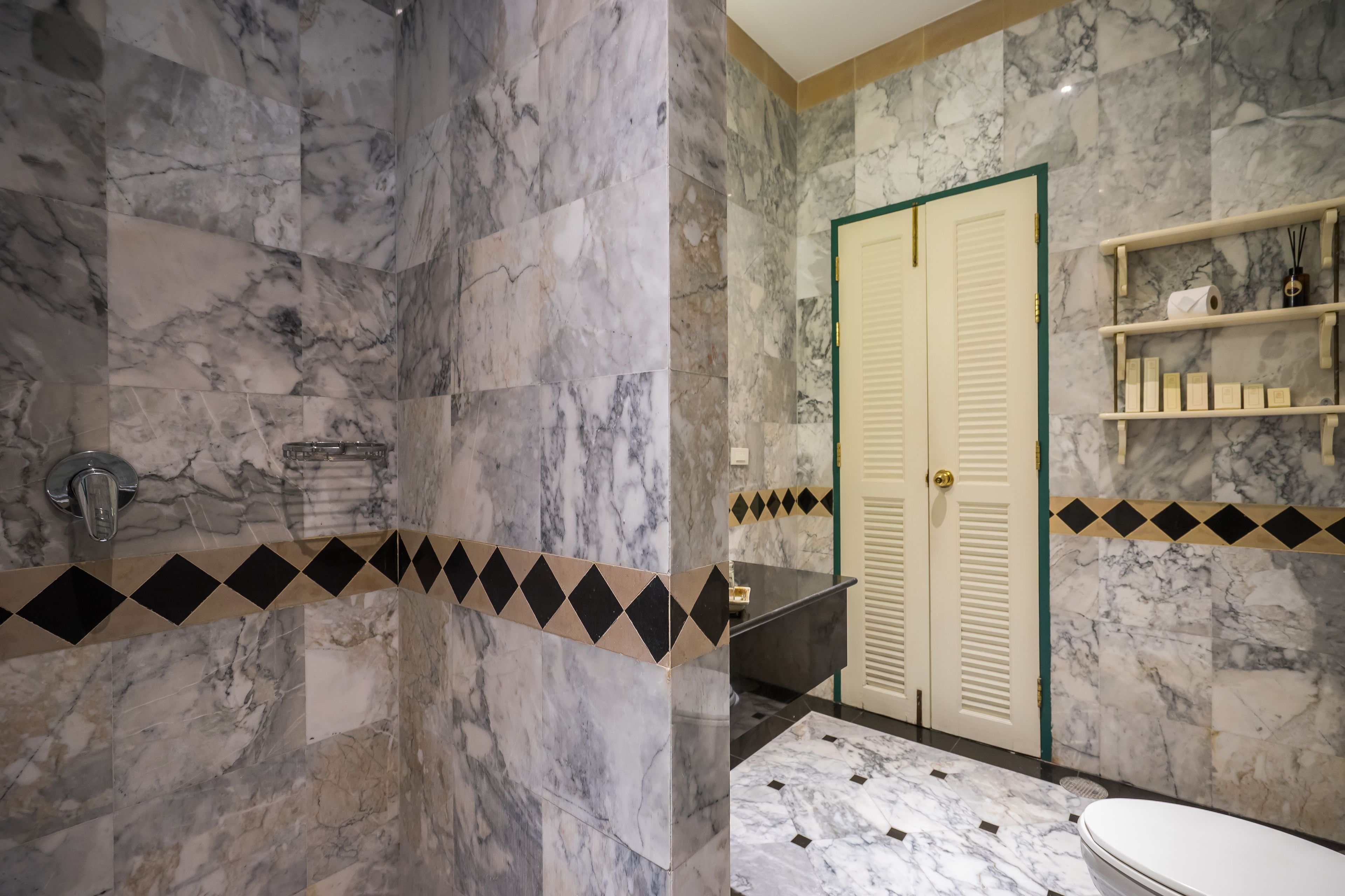Un baño con paredes de mármol, una bañera, un inodoro y zona de ducha.