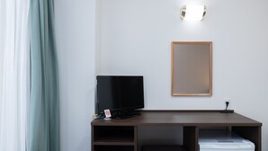 Une chambre d’hôtel équipée d’un bureau, d’une télévision, d’une imprimante et d’un miroir.