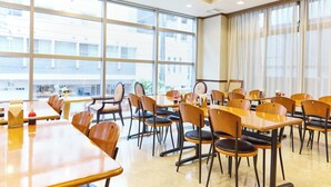 Un vaste espace dédié à la salle à manger, doté de grandes fenêtres, de nombreuses tables et de chaises.