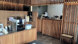 Ein Empfangsbereich mit Holztresen, Kaffeemaschine und einem kleinen Tisch.