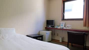 Una habitación de hotel con una cama, un escritorio con ordenador, una silla y una ventana.