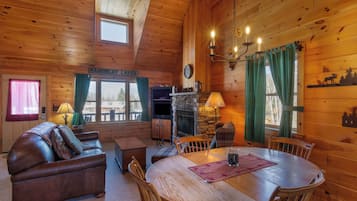 Interior acogedor de una cabaña con chimenea, muebles de madera y vistas al exterior.