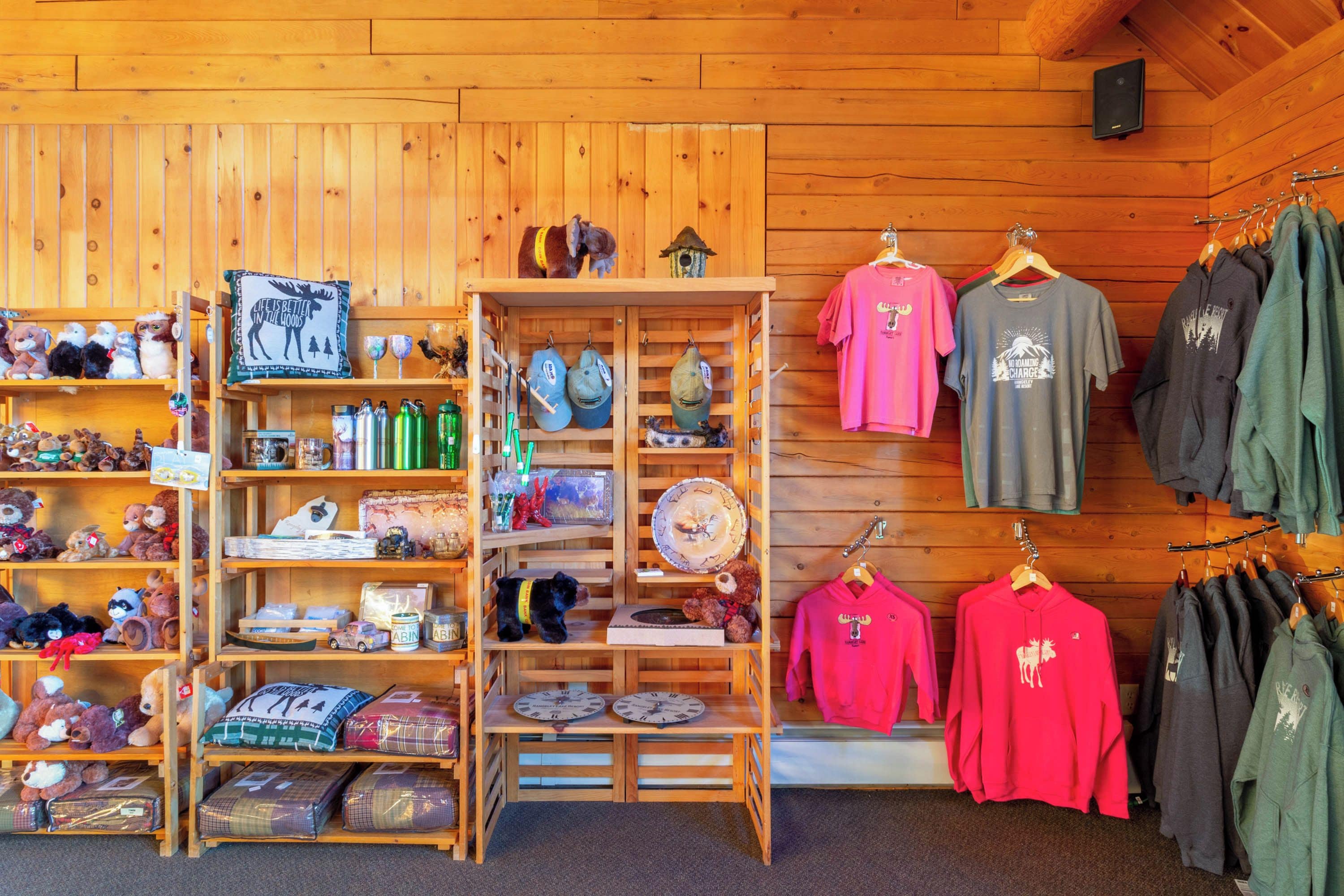 A wooden interior with shelves displaying various items including plush toys, hats, and clothing.