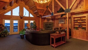 A log cabin interior with a fireplace, leather sofa, and a chandelier.