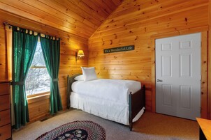 Un dormitorio de cabaña de madera con una cama, una lámpara de pared y una puerta.