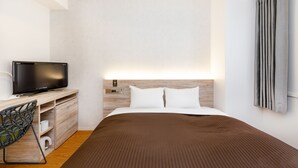Ein modernes Hotelzimmer mit Bett, Fernseher, Schreibtisch und Stuhl.