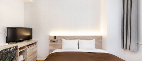 A modern hotel room with a bed, a TV, a desk, and a chair.
