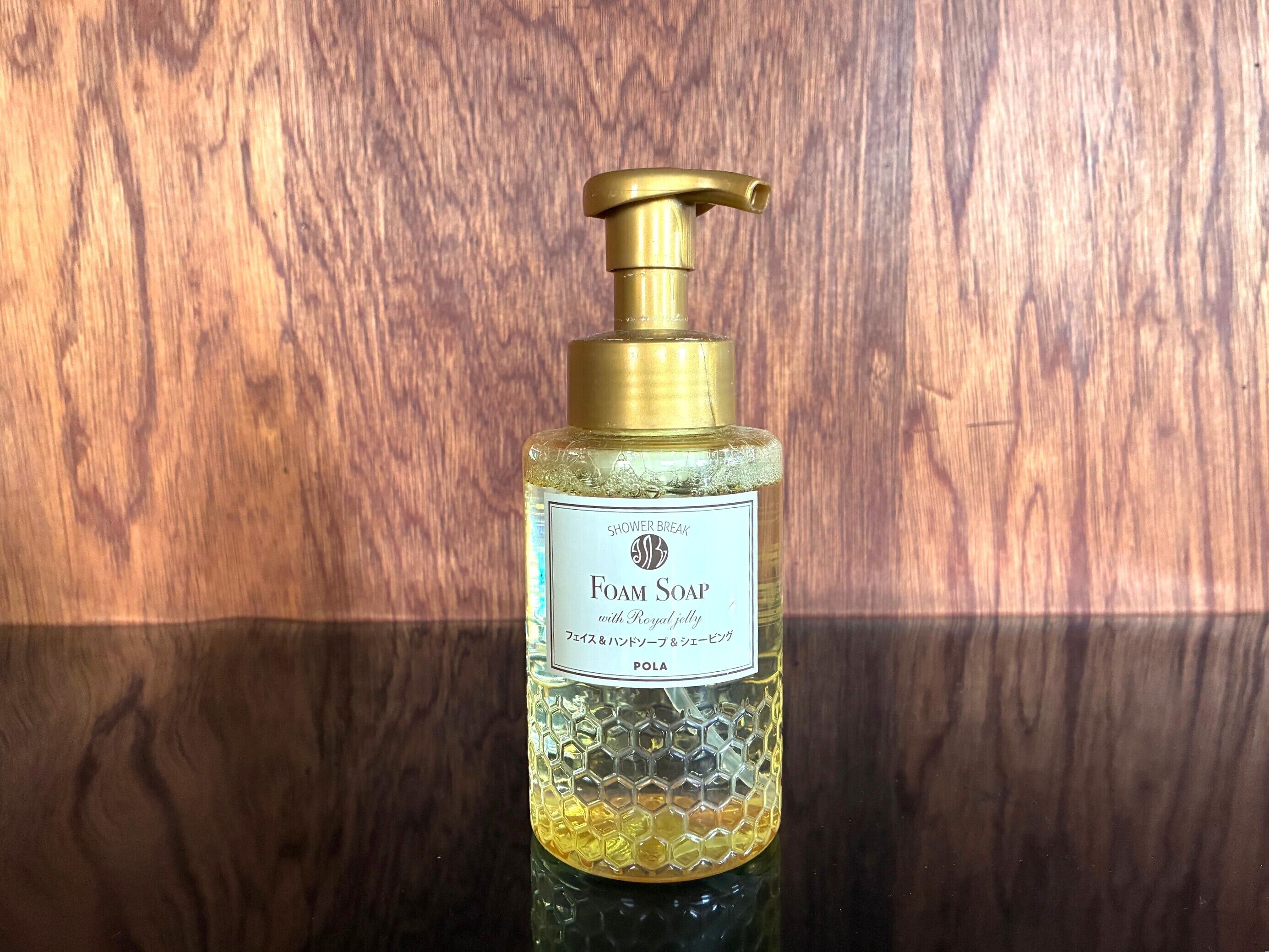 A bottle of Foam Soap with Royal jelly, with a pump dispenser, against a wooden background.