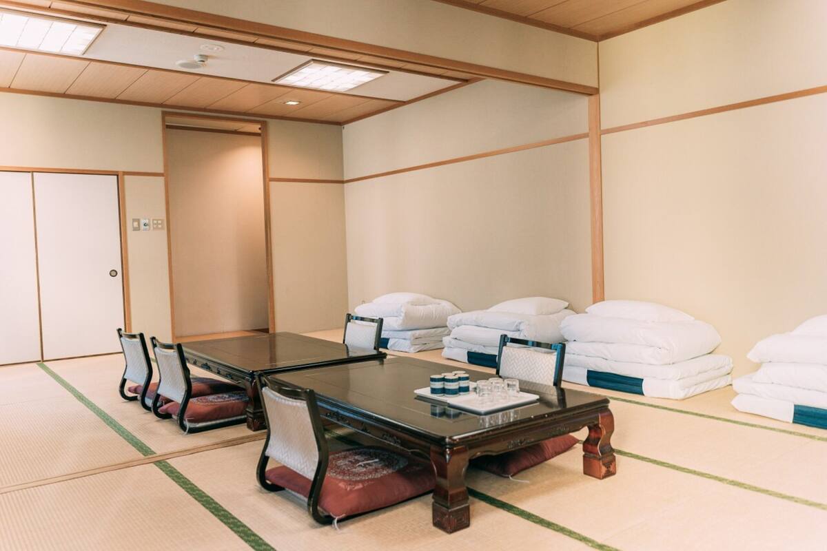 A traditional Japanese-style room with tatami flooring, a low wooden table, and several white pillows.