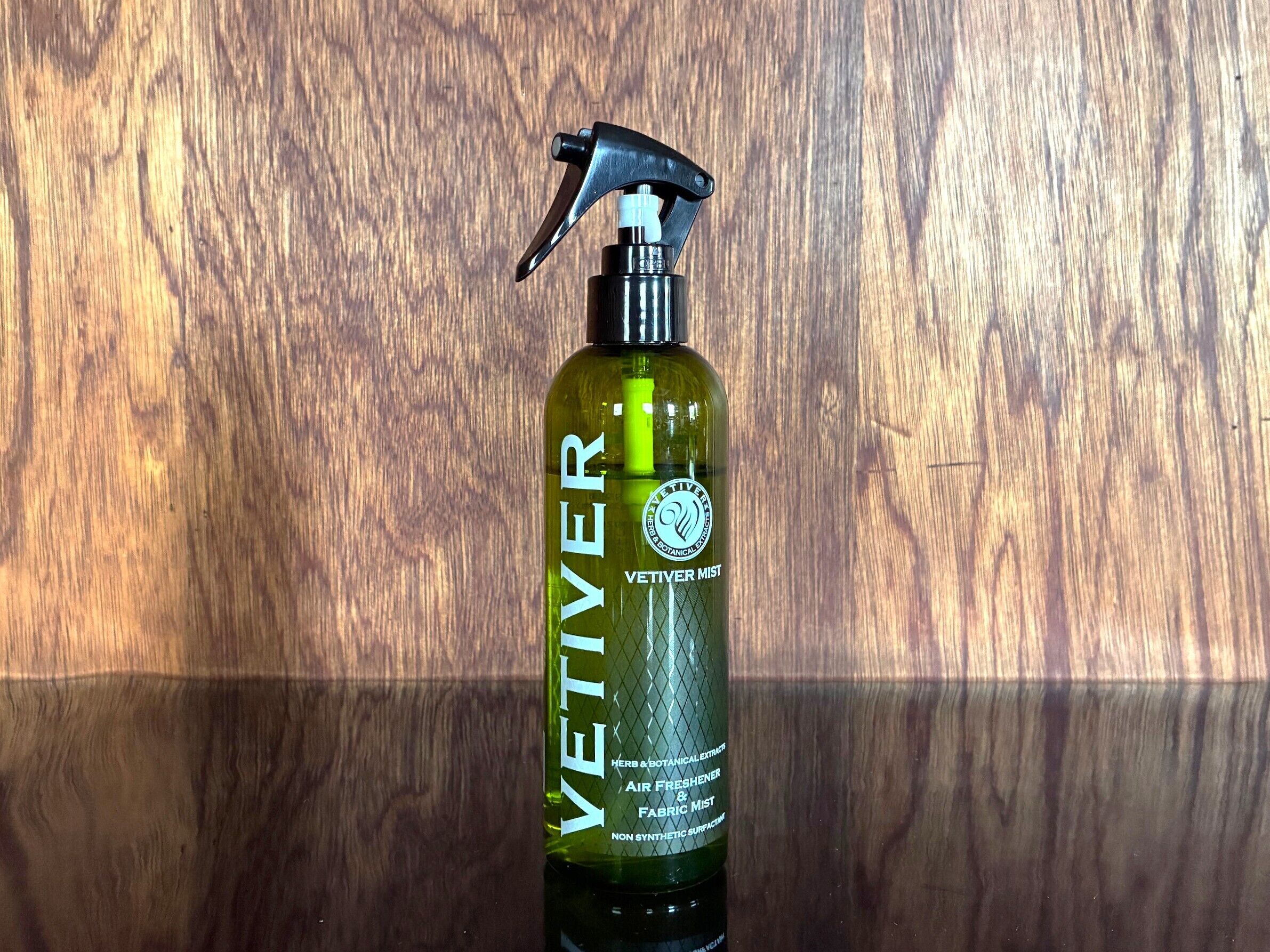 A bottle of VETIVER mist with a spray nozzle, placed against a wooden background.