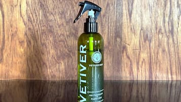 A bottle of VETIVER mist with a spray nozzle, placed against a wooden background.
