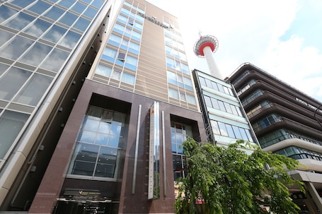A modern hotel building with a prominent tower in the background.
