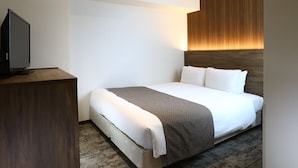 Et hotelværelse med en seng, et fjernsyn på en trækommode og en vægmonteret lampe.