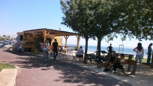 Un café frente a la playa con terraza y vistas al mar.