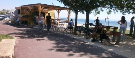 A beachside café with outdoor seating and a view of the sea.