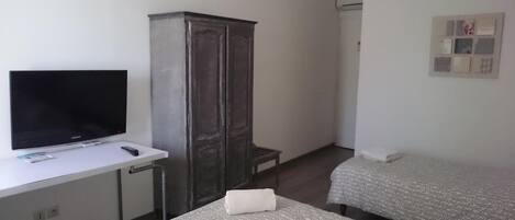 Habitación de hotel con televisión, armario y dos camas.