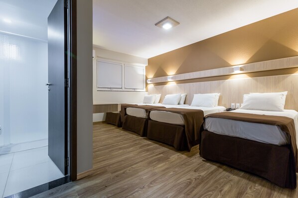 Habitación de hotel con dos camas, un escritorio y un ventanal grande.