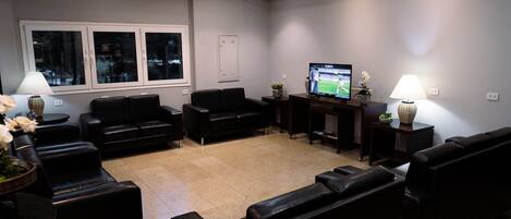 A modern waiting area with leather sofas, a television, and two lamps.