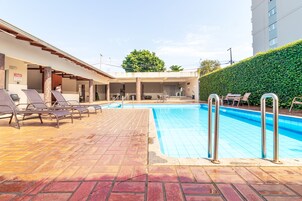 Una piscina al aire libre, sillones reclinables de piscina