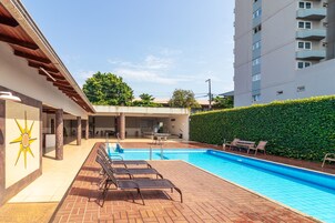 Una piscina al aire libre, sillones reclinables de piscina