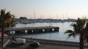A marina with boats docked, a bridge, and a road with vehicles.