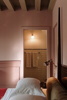 Un dormitorio con cama, mesita de noche, lámpara y puerta que da a un baño con una toalla colgada en la pared.