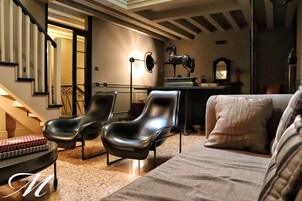 Una sala de estar moderna con un sofá, dos sillones negros, una mesa de centro y una estatua decorativa de un caballo.