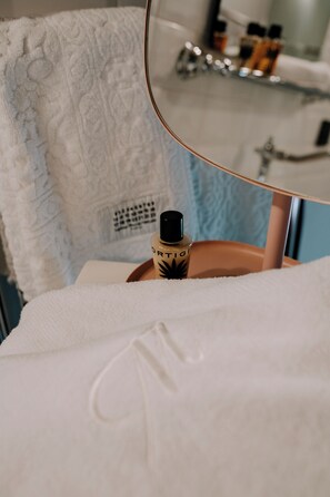 A bathroom with a towel, a bottle of lotion, and a mirror reflecting a sink and toiletries. - Maison Matilda (Treviso)