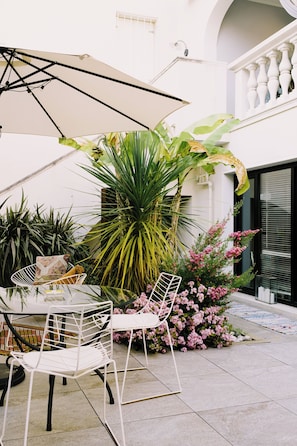 Un espace patio aménagé avec une table et des chaises, entouré de plantes et de fleurs en pot.