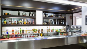 Uma área de bar com diversas prateleiras de garrafas de bebidas, uma máquina de café e uma pia.