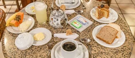 A round table with breakfast items including toast, butter, jam, a teapot, and a cup of coffee.