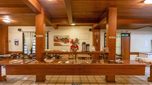 A hotel reception area with a long wooden counter, chairs, and a coffee machine. - VOA Samuka Hotel (Florianópolis)