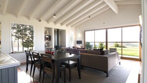 Un vaste espace de vie comprenant une table à manger, des chaises, un canapé et une grande fenêtre donnant sur l’extérieur.