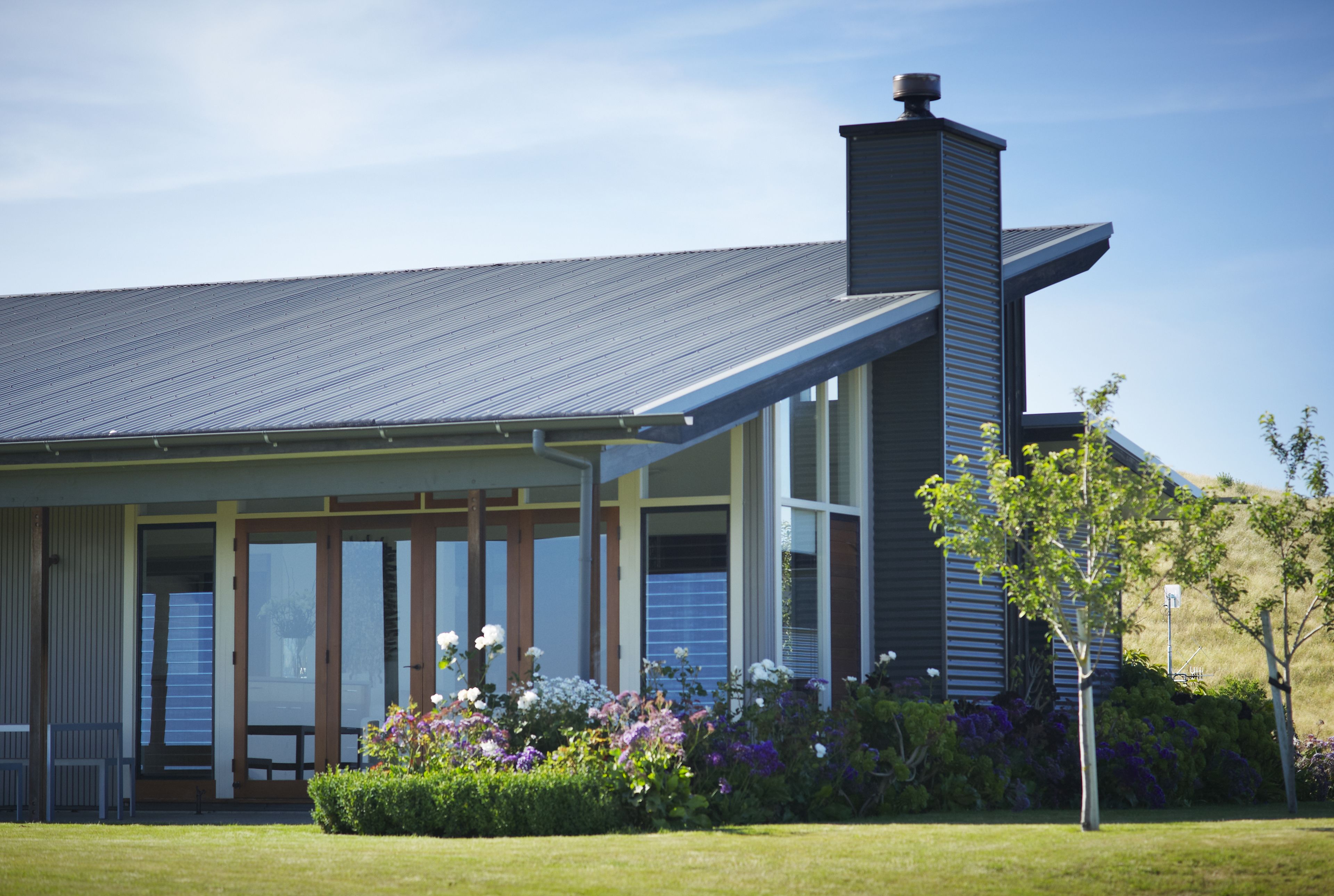 A modern house with a sloped roof, large windows, and a chimney.