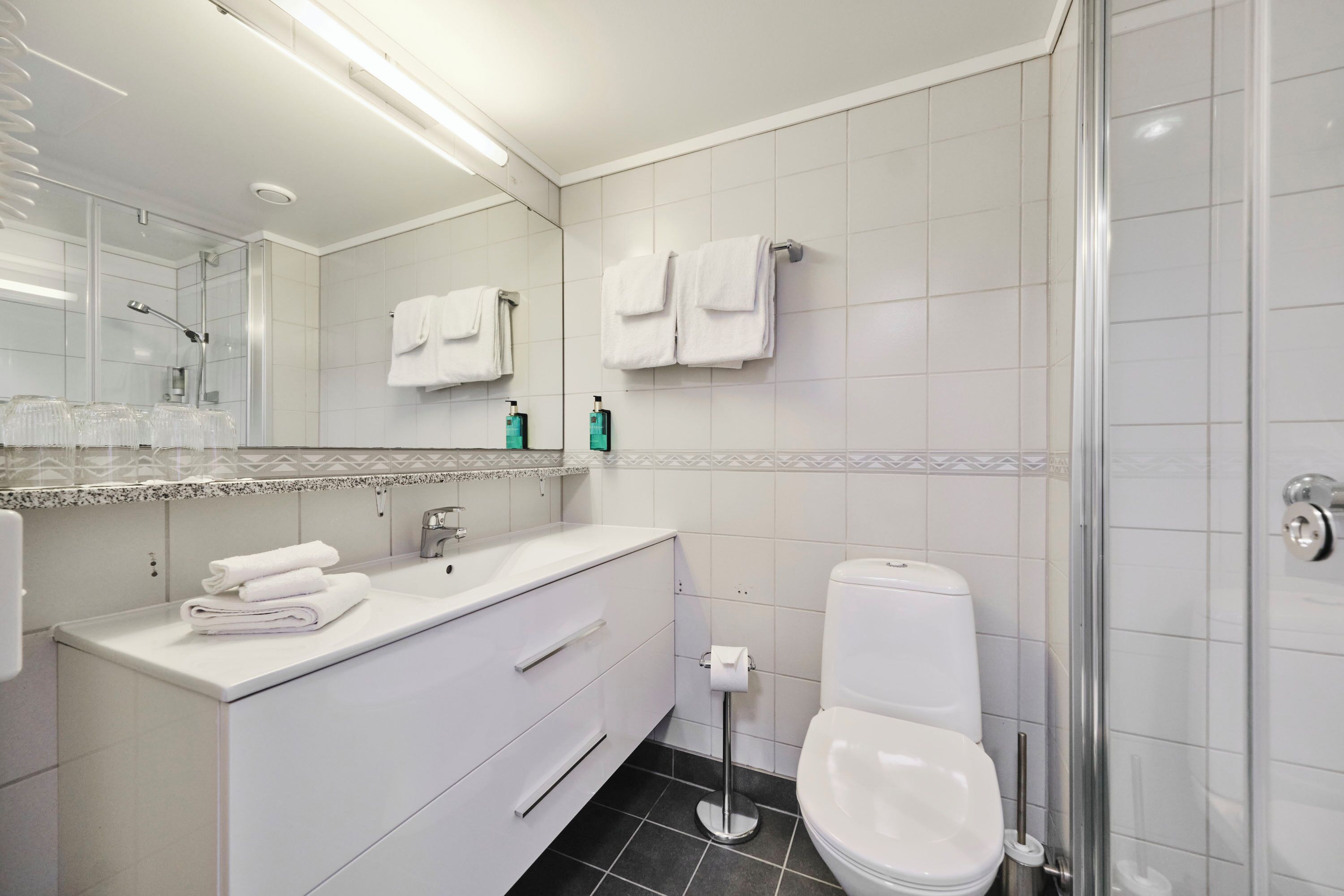 A modern bathroom with a glass shower enclosure, white vanity with a sink, and a toilet.