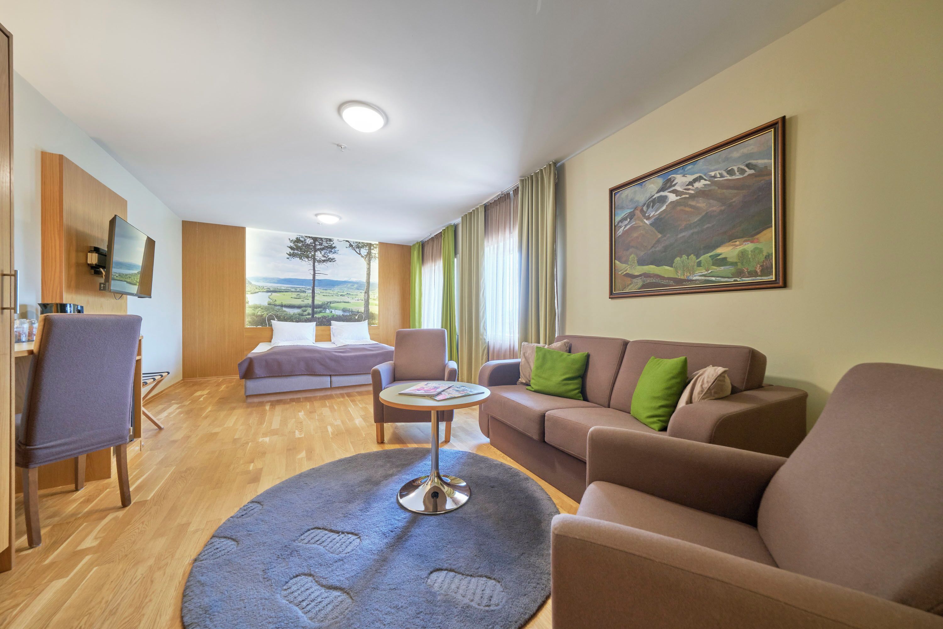 Una sala de estar moderna con un sofá, sillones, una mesita de centro y un televisor montado en la pared.