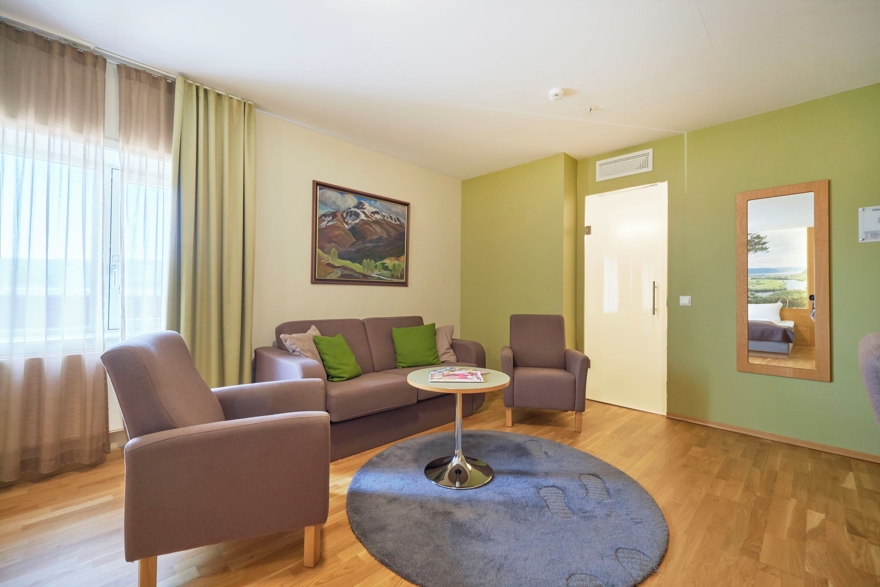 Una sala de estar con un sofá, dos sillones, una mesita de centro y un cuadro en la pared.