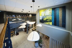 Un intérieur moderne agrémenté d’un grand tableau abstrait, de plusieurs luminaires suspendus et d’un escalier.