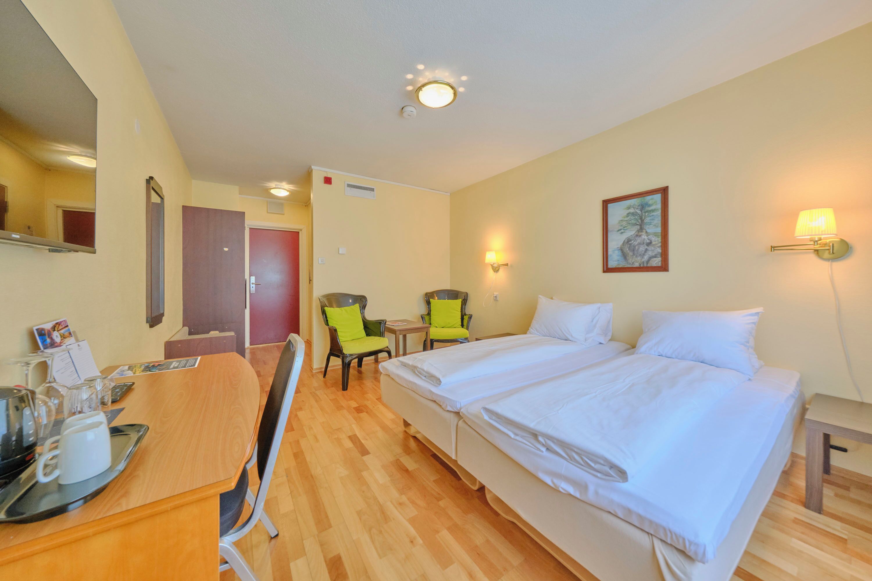 Habitación de hotel con cama, escritorio, sillas y un cuadro en la pared.