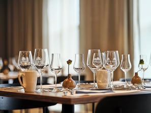 Taula de dinar preparada amb diversos vasos de vi i una gerra, amb un fons borrat que suggereix un restaurant.