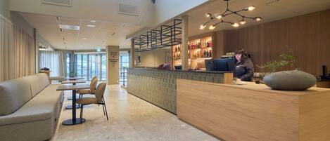 Eine moderne Hotelhalle mit Rezeption, Sitzgelegenheiten und einer Bar.