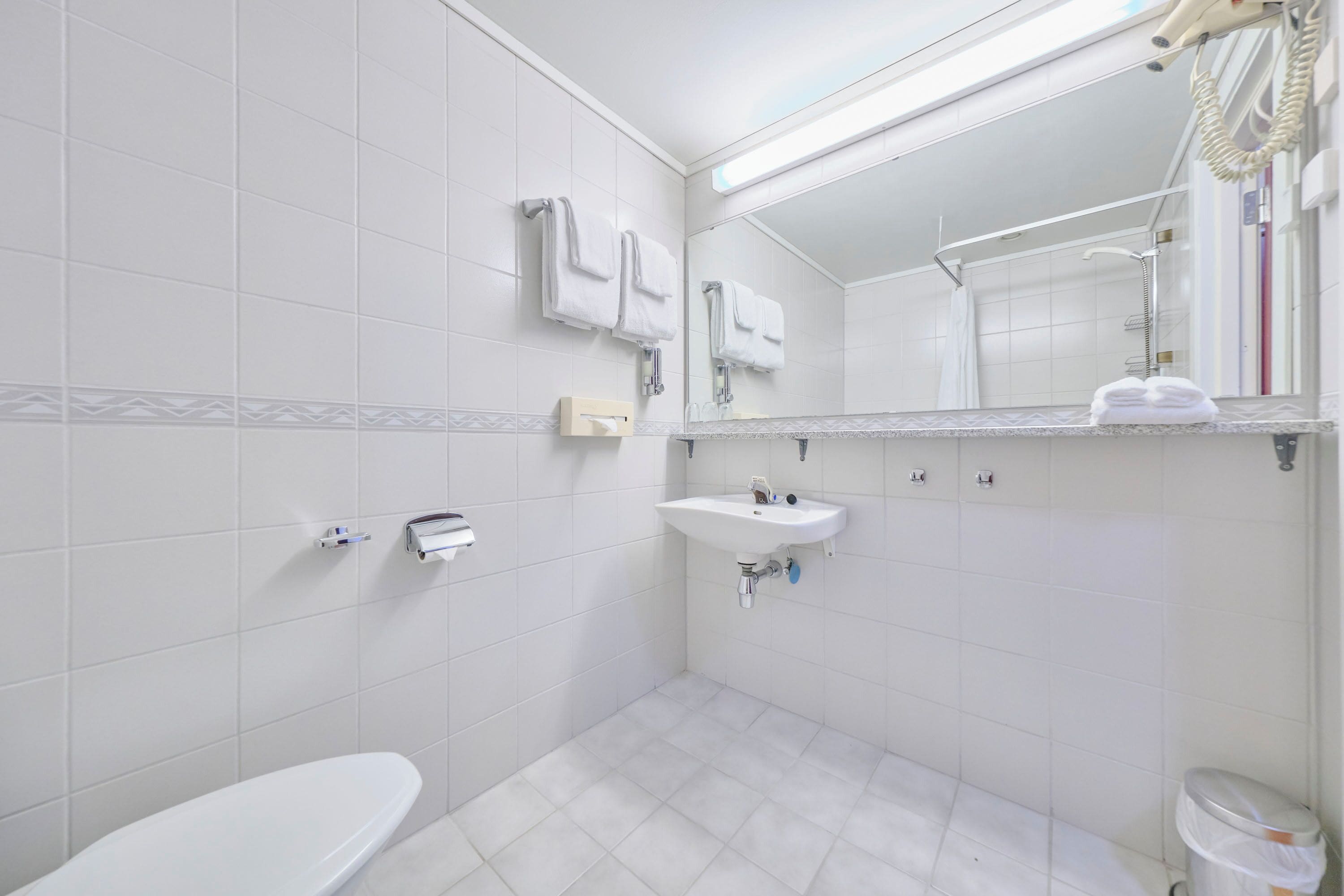 A modern bathroom with a toilet, sink, and shower.