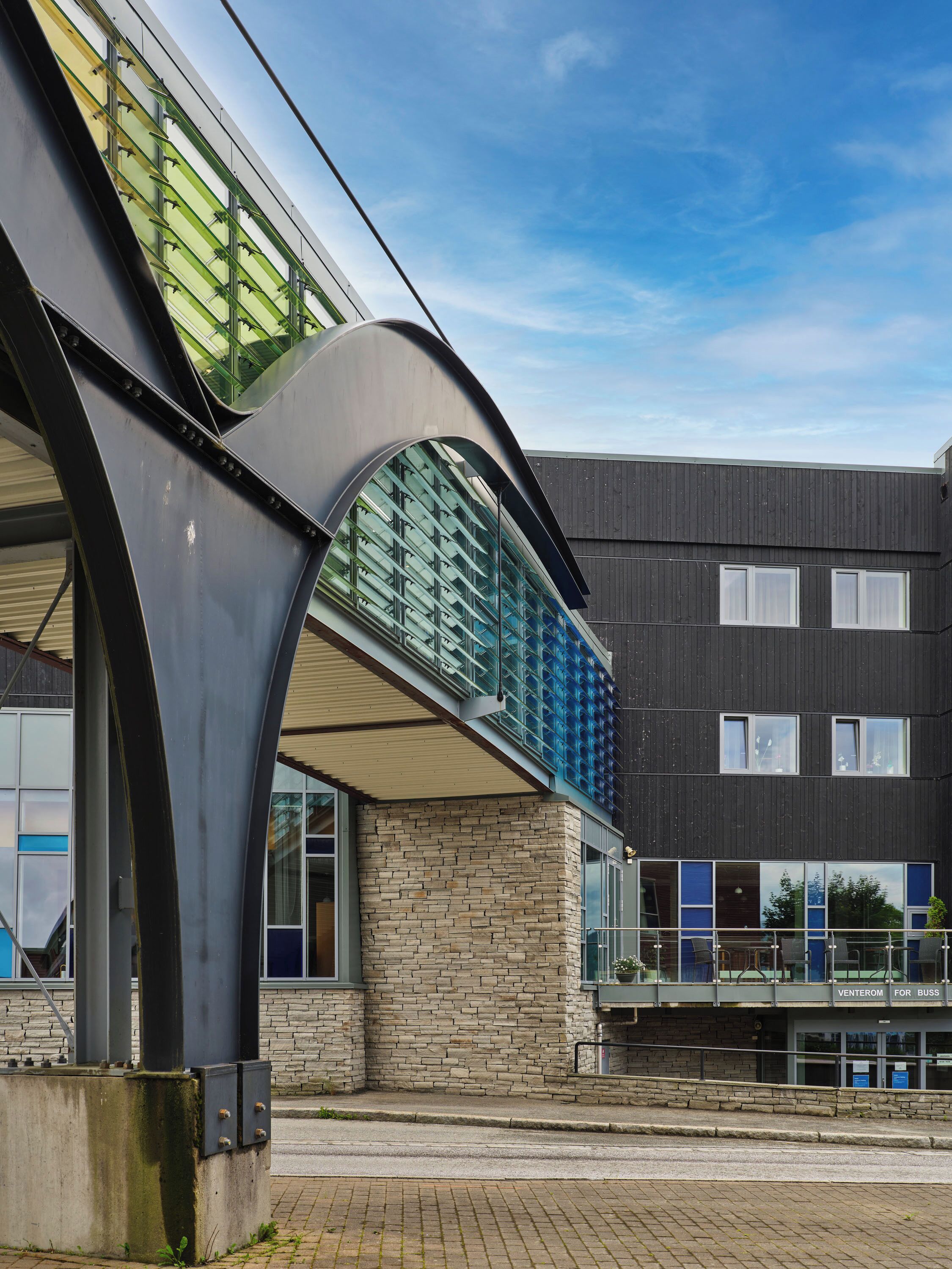A modern building with a glass and metal structure, a brick facade, and a flat roof.