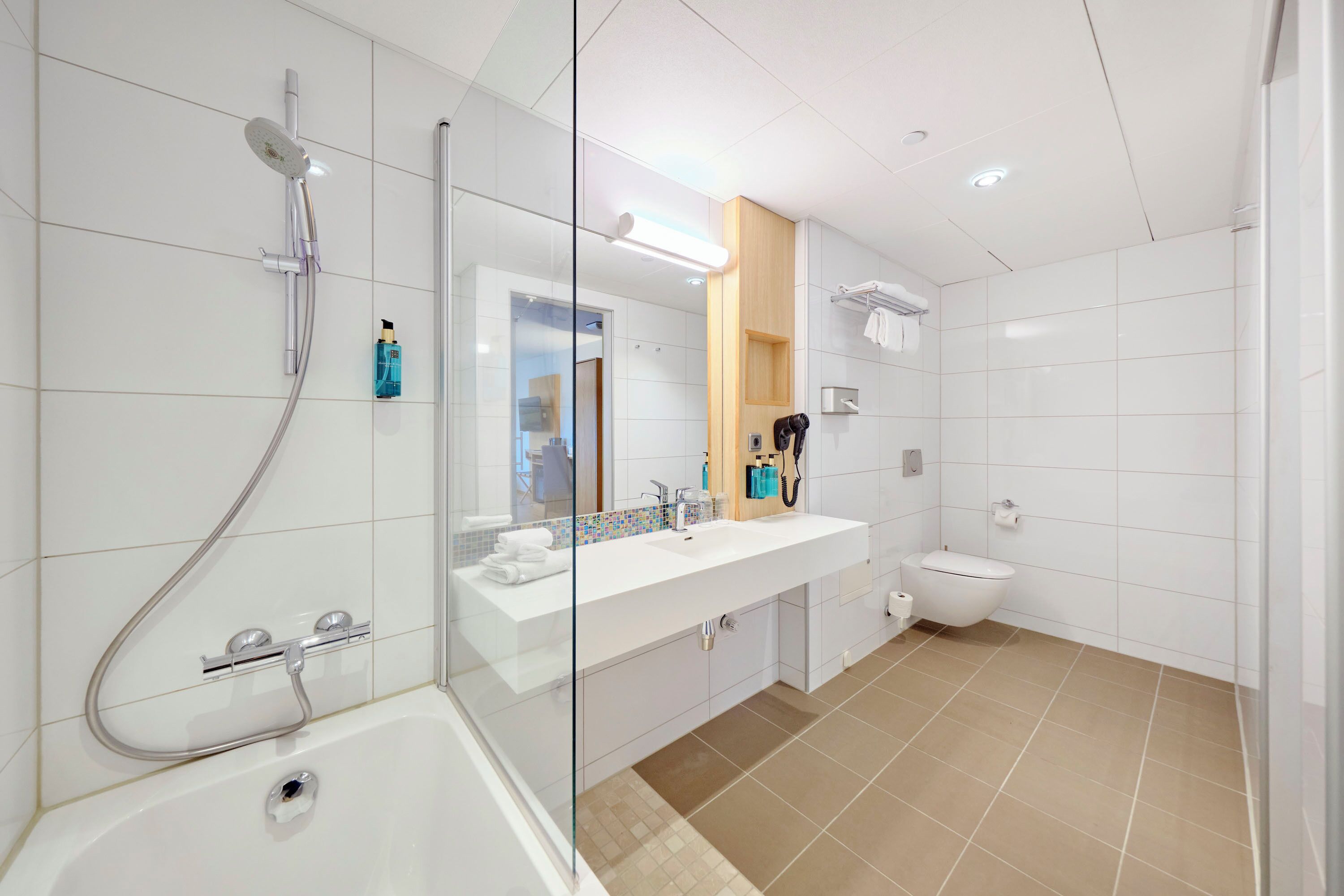 Une salle de bain moderne avec une douche à parois de verre, un lavabo blanc avec un miroir et des toilettes.