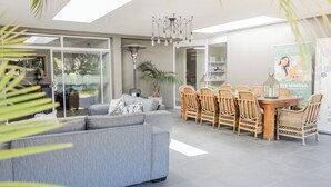 Una sala moderna con un sofá gris, sillas de mimbre y una mesa de comedor.