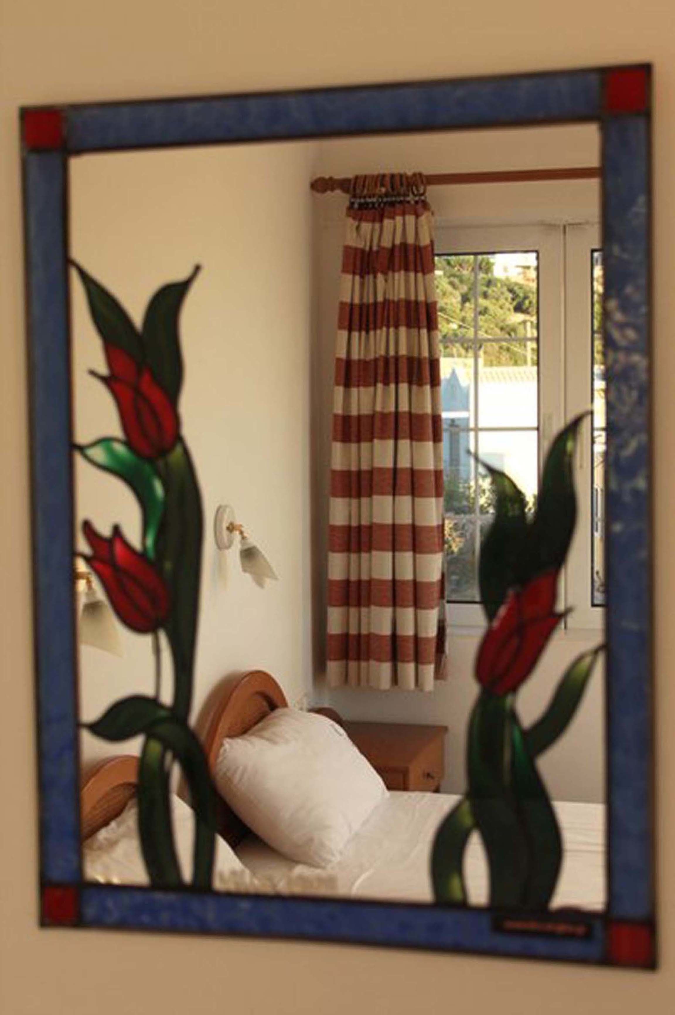 A bedroom with a bed, a window with curtains, and a wall-mounted lamp.