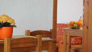 Une table à manger en bois, avec une plante en pot, une chaise et une nappe.