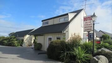 Jade Court Motor Lodge features a simple design with a flat roof and a small porch area surrounded by well-maintained landscaping.
