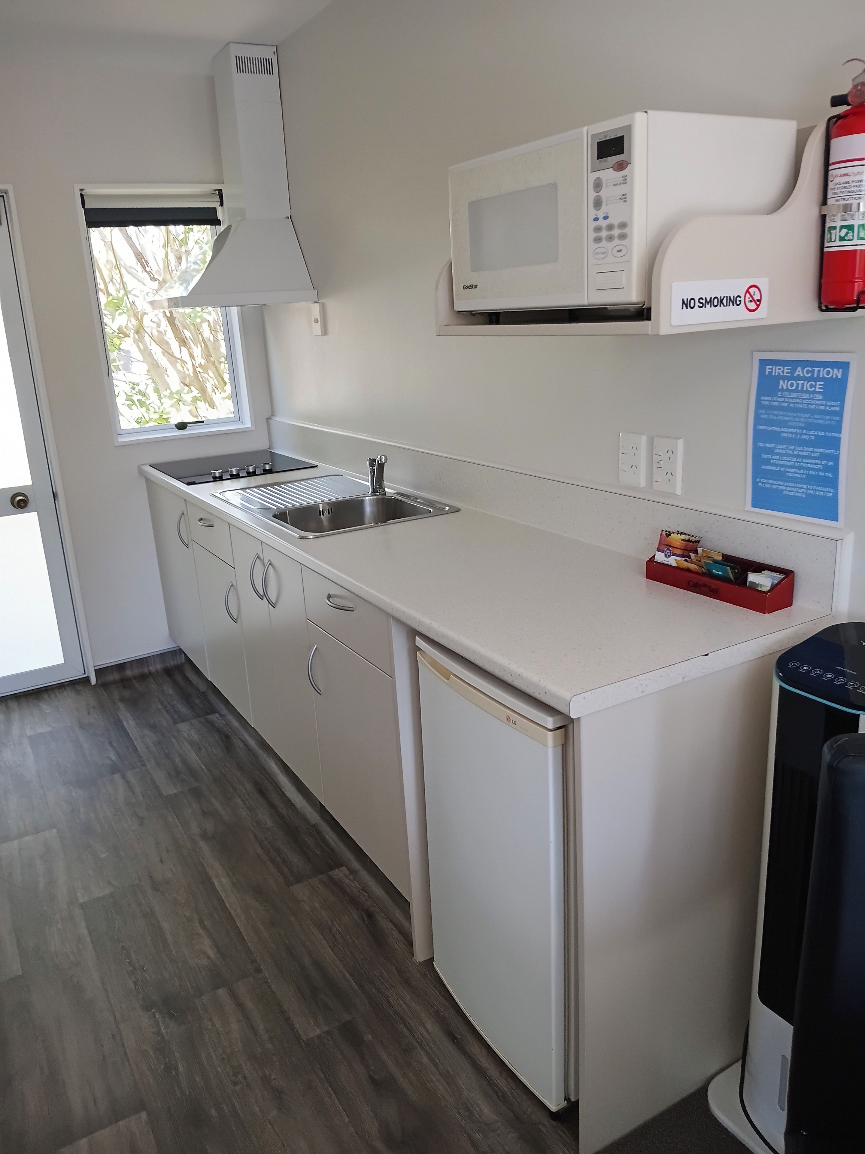 A modern kitchen with a built-in microwave, a sink, and a compact dishwasher.