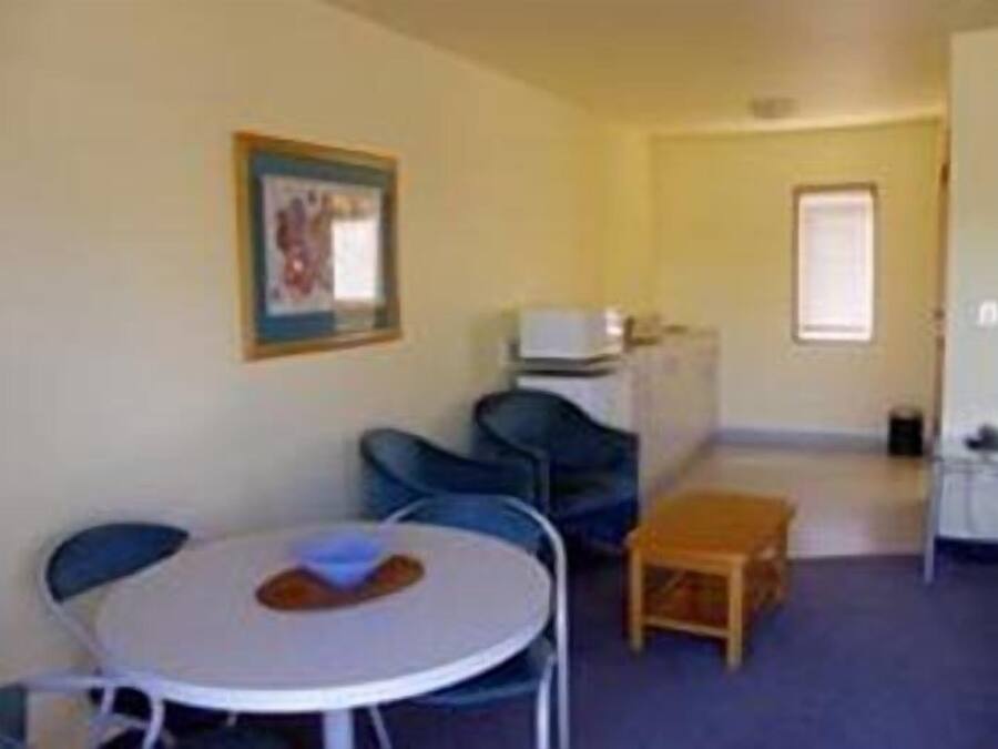 A small room with a round table and chairs, a television, and a window.